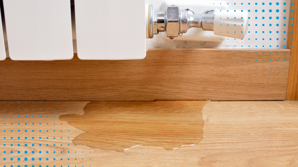 An image of water leaking from a radiator onto a hardwood floor.