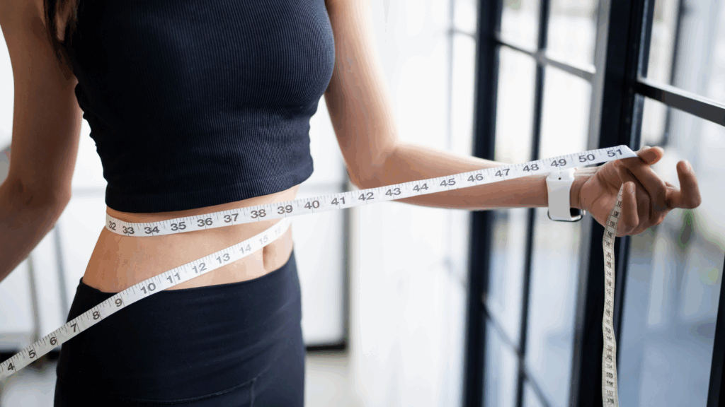Measuring waist weight loss with a measuring tape.